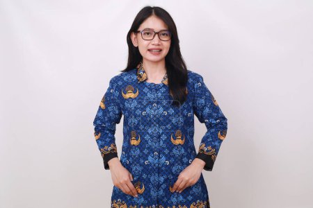 Photo for Friendly Asian female in batik korpri, indonesian traditional uniform standing with folded hands - Royalty Free Image