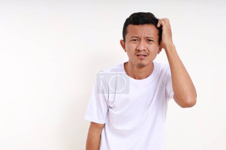 Photo for Confused asian funny man standing while holding his head. Isolated on white background - Royalty Free Image