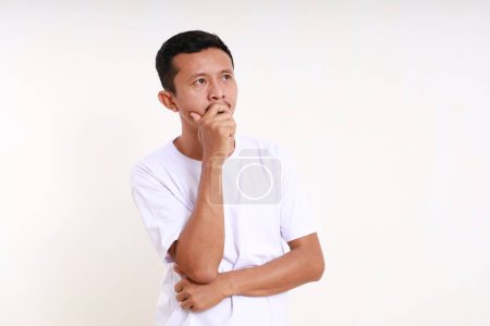 Photo for Thoughtful asian funny man thinking an idea while looking at empty space. Isolated on white - Royalty Free Image