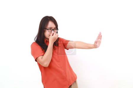 Téléchargez les photos : Jeune femme asiatique debout avec déni geste de la main tout en couvrant son nez. Concept de mauvaise odeur - en image libre de droit