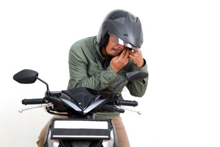 Photo for Asian man having trouble with his eyes while riding motorcycle. Some dust gets into his eyes. Isolated on white background - Royalty Free Image