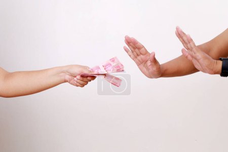 Téléchargez les photos : La main d'un humain donne une pile d'argent à une autre main, qui refuse. Vue latérale. Fond blanc. Le concept de la Journée mondiale de lutte contre la corruption - en image libre de droit