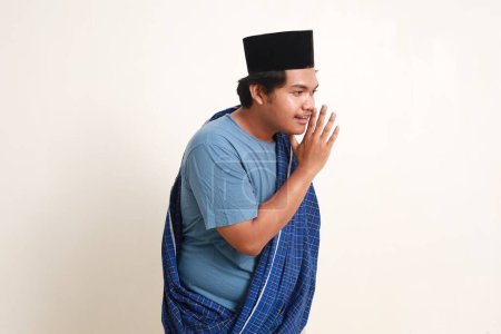 Foto de Chico musulmán asiático susurrando o hablando de lado. Aislado sobre blanco - Imagen libre de derechos