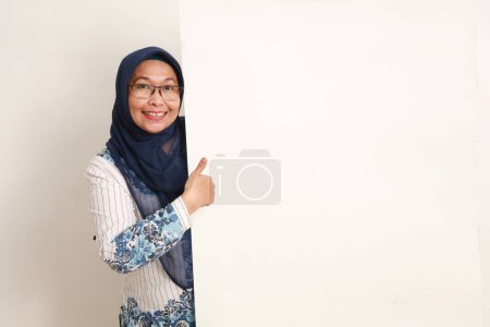 Happy asian elderly woman presenting something on blank board while showing thumbs up