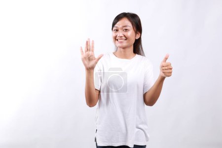 Lächelnd glücklich gut aussehendes asiatisches Mädchen gibt Ratschläge, zeigt sechs Finger als Erklärung der Regeln, macht Punkt, steht weißer Hintergrund