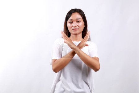 Portrait of young asian woman showing stop, cross prohibition sign, forbid smth, refusing, standing over white background