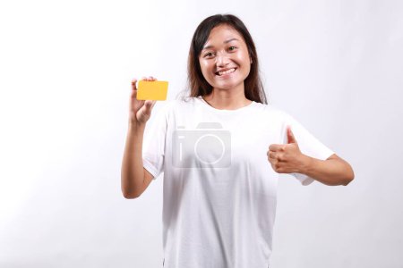 Foto de Joven mujer asiática en ropa casual mostrando tarjeta en blanco y el pulgar hacia arriba gesto, aprobar y recomendar, sonriendo a la cámara, fondo blanco - Imagen libre de derechos