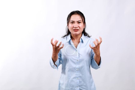 Empörte aggressive asiatische Frau schüttelt frustriert und wütend die Hände, runzelt die Stirn und grimassiert, flucht wütend auf jemanden, ist wütend, steht vor weißem Hintergrund