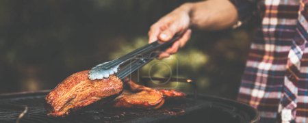 Téléchargez les photos : Famille faisant barbecue de porc croustillant grill dans le camping de fête de dîner la nuit - en image libre de droit