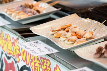 Foto de Kyoto Japón - 25 de mayo de 2018: BBQ Grill vieira y pincho de pulpo es popular comida callejera japonesa en el mercado fresco en Japón - Imagen libre de derechos