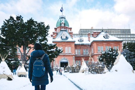 Foto de Mujer viajera con mochila y suéter en temporada de invierno en la ciudad de Sapporo, Hokkaido, Japón - Imagen libre de derechos