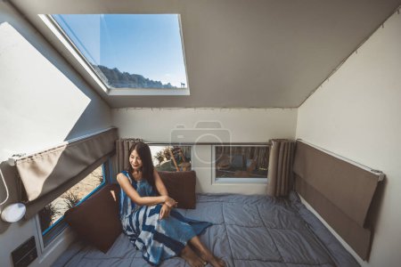 Photo for Travel vacation in campervan concept, Happy traveler asian woman with dress relax inside a camper car recreational vehicle at bedroom in Mon Jam, Chiang Mai, Thailand - Royalty Free Image