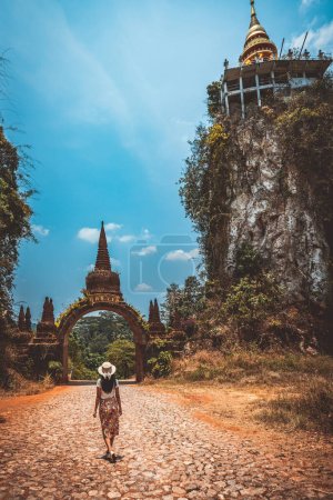 Foto de Viajes concepto de vacaciones de verano, Feliz viajero solo mujer asiática con sombrero relajarse y hacer turismo en el templo en Khao Na Nai Luang Dharma Park, Surat Thani Province, Tailandia - Imagen libre de derechos