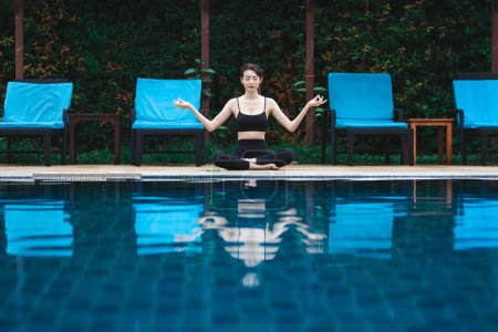 Téléchargez les photos : Fitness femme asiatique faisant méditation de yoga pour se détendre et en bonne santé à côté du fond de la piscine, Sport de plein air et concept sain - en image libre de droit
