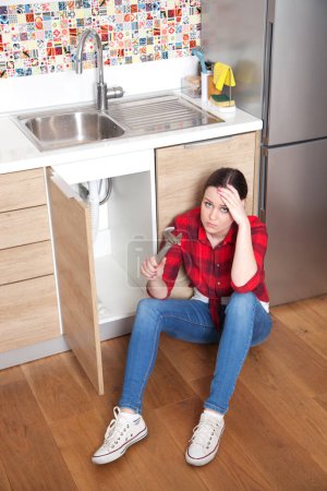 Téléchargez les photos : Jeune femme ayant du mal à réparer l'évier de cuisine par elle-même - en image libre de droit