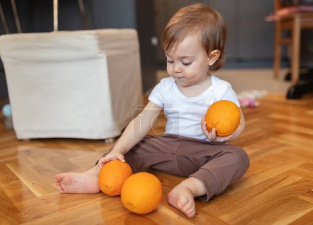 Téléchargez les photos : Adorable enfant d'un an jouant avec orange, faible profondeur de champ - en image libre de droit