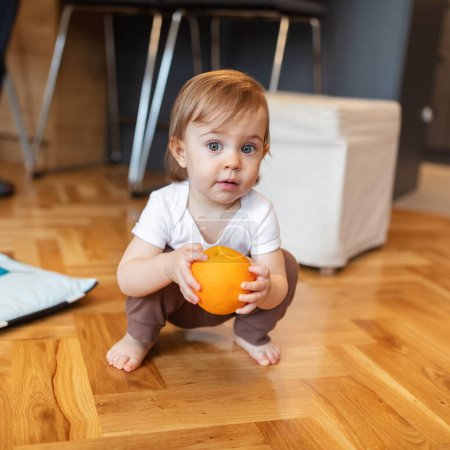 Téléchargez les photos : Adorable enfant d'un an jouant avec orange, faible profondeur de champ - en image libre de droit