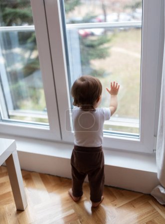 Photo for Portrait of adorable one year old child looking trough the window, shallow depth of field - Royalty Free Image