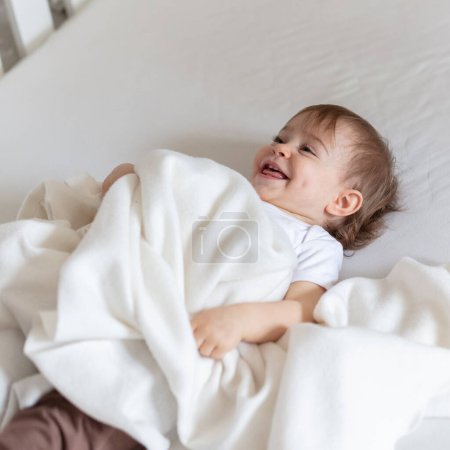 Photo for Adorable 12 months old child on bed playing with blanket - Royalty Free Image