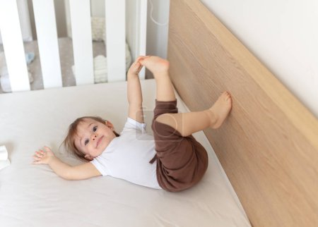Téléchargez les photos : Adorable enfant de 12 mois au lit jouant et riant - en image libre de droit