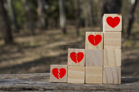 Photo for Concept of healing wounds of the Heart, wooden cubes placed on stairs and on each step you see a red heart that is being repaired - Royalty Free Image