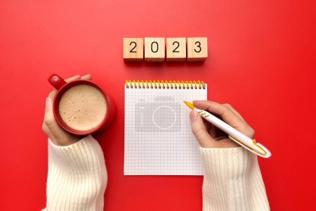 Téléchargez les photos : Un stylo, un carnet, une tasse de café et l'inscription : 2023. Établir des plans et des objectifs pour la nouvelle année - en image libre de droit