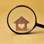 Wooden house through a magnifying glass. Housing Evaluation Symbol