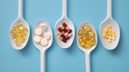 Photo for Tablets, capsules, dietary supplements, vitamins on white spoons. Medical background with pills - Royalty Free Image