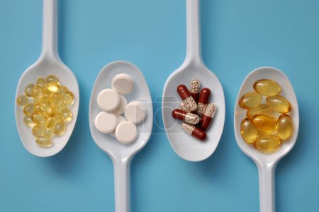 Tabletten, Kapseln, Nahrungsergänzungsmittel, Vitamine auf weißen Löffeln. Medizinischer Hintergrund mit Pillen