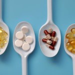 Tablets, capsules, dietary supplements, vitamins on white spoons. Medical background with pills