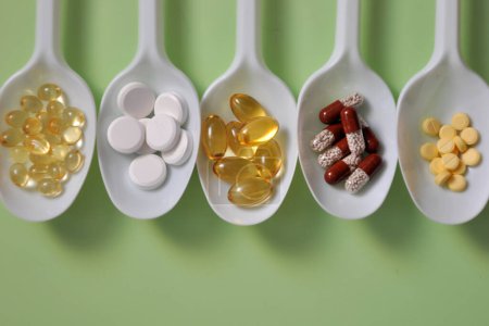 Foto de Comprimidos, cápsulas, suplementos dietéticos, vitaminas en cucharas blancas. Fondo médico con pastillas - Imagen libre de derechos
