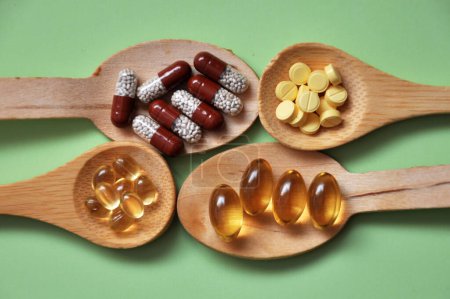 Tablets, capsules, dietary supplements, vitamins in wooden spoons. Medical background