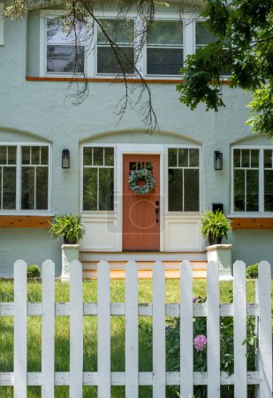 Téléchargez les photos : Une jolie maison a une entrée accueillante et une simple clôture blanche - en image libre de droit