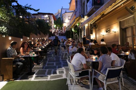 Téléchargez les photos : Les gens s'assoient sur la terrasse d'un café dans le quartier de Plaka à Athènes, Grèce le 15 août 2022. - en image libre de droit