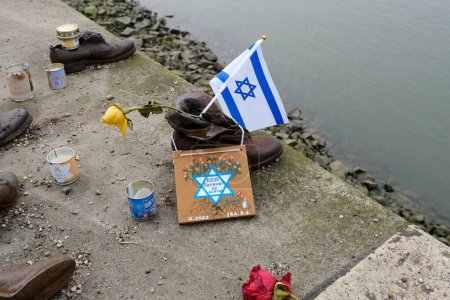 Photo for The flag of Israel in  the memorial of shoes remembering the Holocaust victims on the bank of the River Danube in downtown Budapest, Hungary on December 22, 2022. - Royalty Free Image