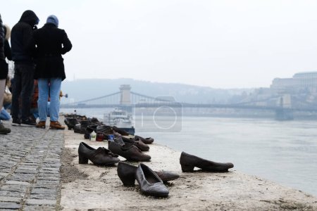 Photo for Tourist visit the memorial of shoes remembering the Holocaust victims on the bank of the River Danube in downtown Budapest, Hungary on December 22, 2022. - Royalty Free Image