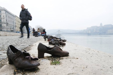 Téléchargez les photos : Tourist visit the memorial of shoes remembering the Holocaust victims on the bank of the River Danube in downtown Budapest, Hungary on December 22, 2022. - en image libre de droit