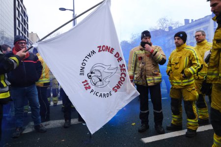 Foto de A firefighter lights a banner on fire as he protests with other emergency personnel for better working conditions during a demonstration in Brussels, Belgium on Jan. 27, 2023. - Imagen libre de derechos