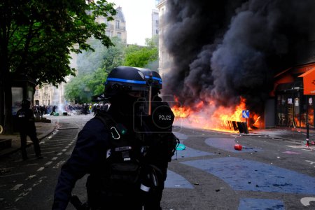 Photo for French riot police officers stand near a fire in a building during the May Day labour march, a day of mobilisation against the French pension reform law  in Paris, France May 1, 2023. - Royalty Free Image