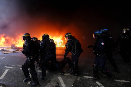 Photo for French riot police officers stand near a fire in a building during the May Day labour march, a day of mobilisation against the French pension reform law  in Paris, France May 1, 2023. - Royalty Free Image