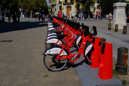 Photo for Barcelona, Spain - October 2, 2021 - Red bicycles belonging to the public transportation sharing service Bicing line the boardwalk in the Barcelonetta neighborhood - Royalty Free Image