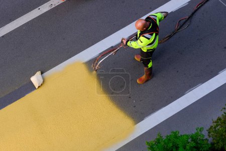 Téléchargez les photos : Un employé municipal utilisant un pulvérisateur de peinture applique des marquages jaunes sur un passage piétonnier à Bruxelles, Belgique, le 4 juillet 2023. - en image libre de droit