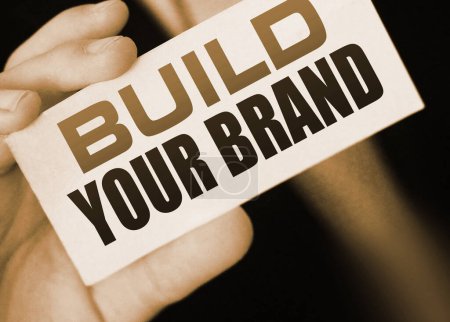 Foto de Empresario sosteniendo una tarjeta con texto Construye tu marca. Concepto de marketing para startups. - Imagen libre de derechos