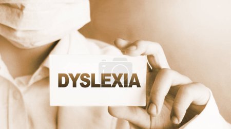 Dislexia palabra en tarjeta. El médico guarda una tarjeta con el nombre del diagnóstico de dislexia. Enfoque selectivo. Concepto médico. 