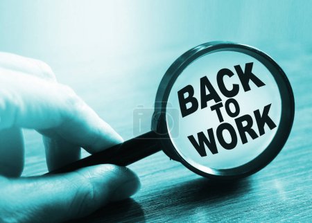 Photo for Back to work is written under magnifier in hand. - Royalty Free Image