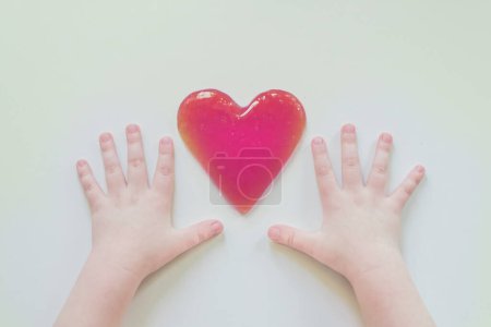 Foto de Slime antisress the child plays. Hands of a child. Heart shaped mucus - Imagen libre de derechos