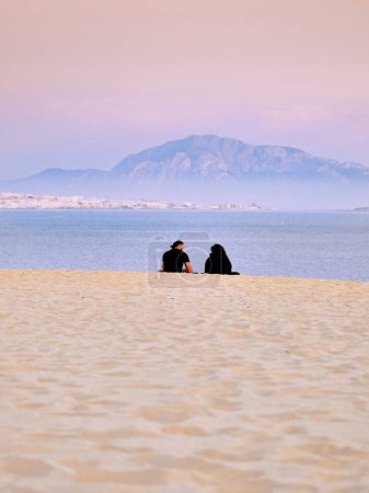Photo for Romantic couple watching sea and sunset on valdevaqueros dune tarifa and musa jebel on background - Royalty Free Image