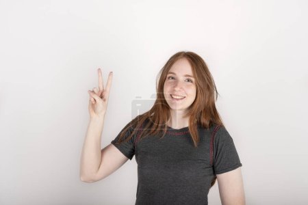 Photo for Portrait of young red haired woman celebrating, happy, with a winning expression, on pure background - Royalty Free Image