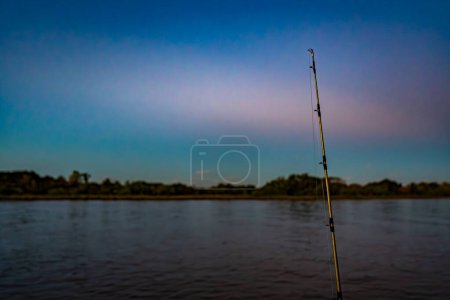 Fishing rod with reel resting on the beach wall, night time
