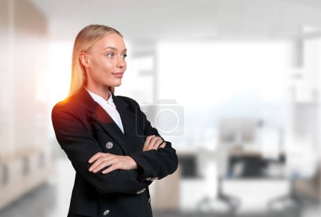 Téléchargez les photos : Attentif attrayant femme d'affaires portant tenue formelle debout dans la pose de bras croisés regardant loin du lieu de travail de bureau en arrière-plan. Concept de modèle, homme d'affaires ambitieux, femme inspirée - en image libre de droit